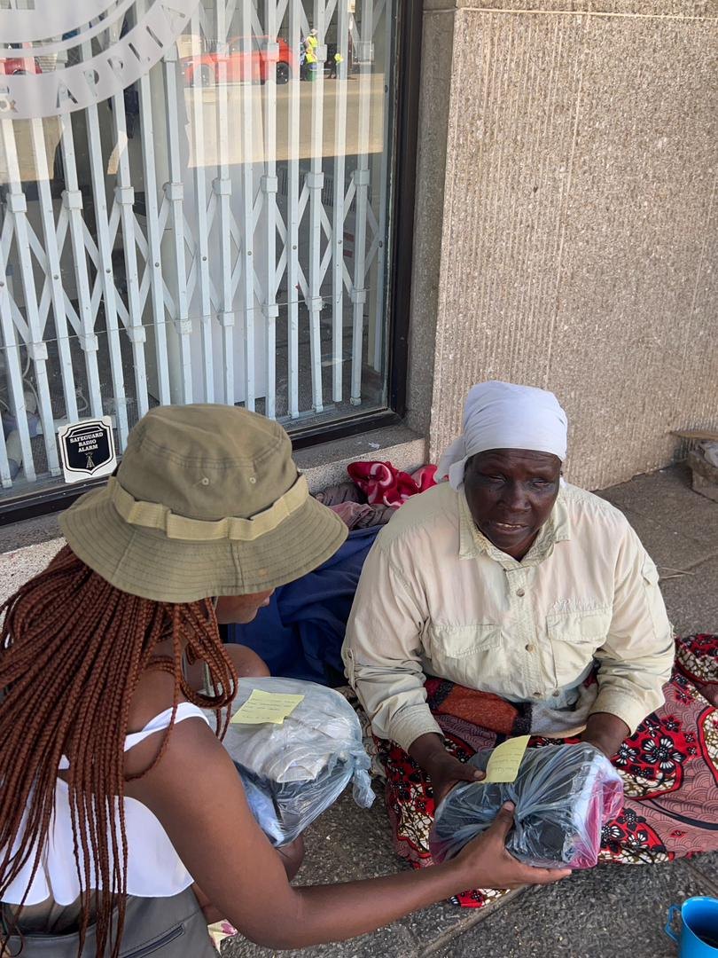 A Save the World Foundation volunteer handing a care package to a woman on the street