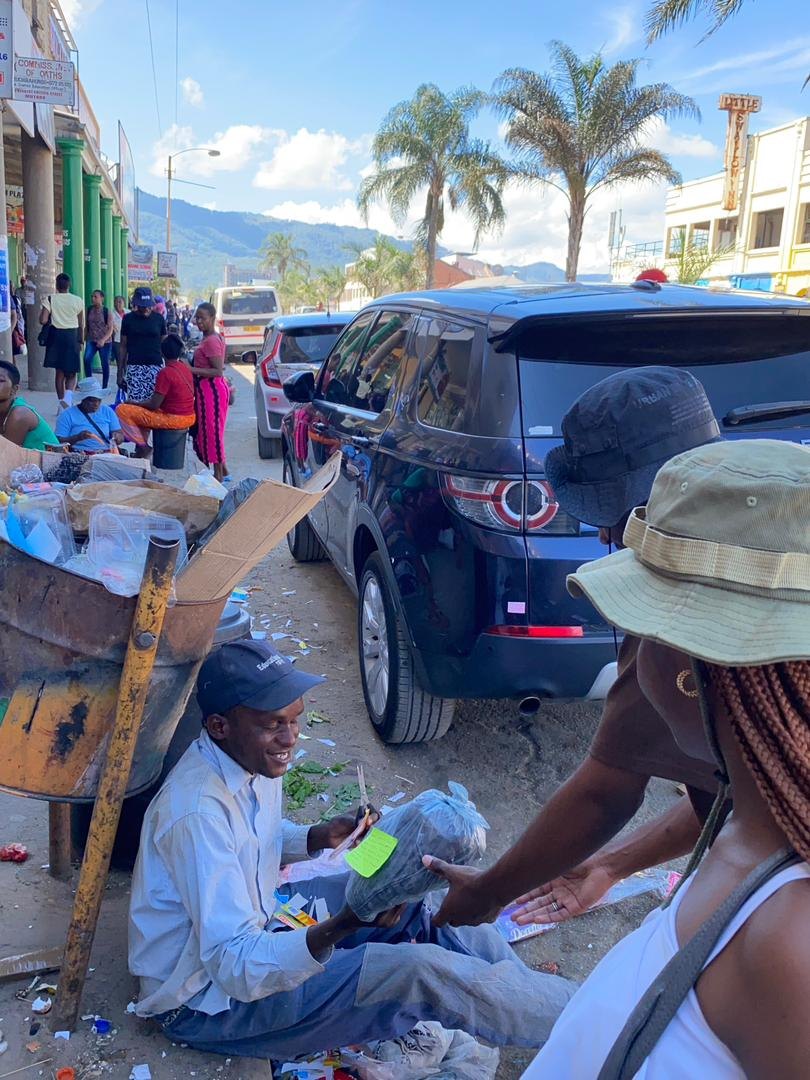 A volunteer handing supplies to a man on a street in Mutare